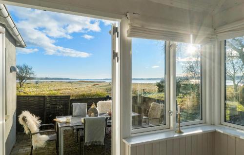 a dining room with a view of the countryside through a window at 3 Bedroom Cozy Home In Nibe in Nibe