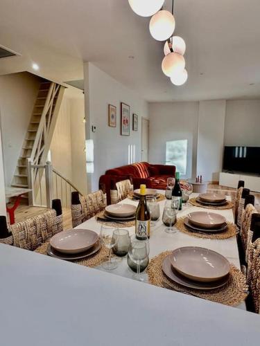 une salle à manger avec une table avec des assiettes et des verres à vin dans l'établissement Maison Henriette - Au plus près de la Cité Médiévale, à Carcassonne