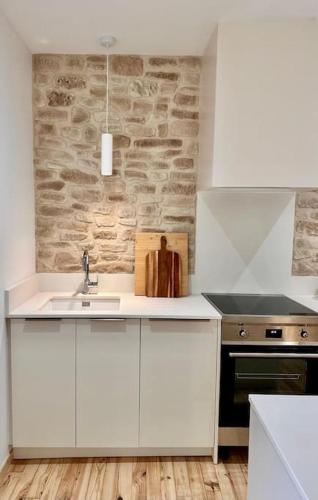 une cuisine avec un évier et un mur en pierre dans l'établissement Maison Henriette - Au plus près de la Cité Médiévale, à Carcassonne