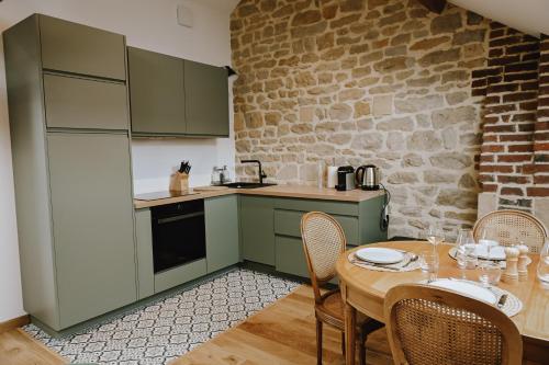 une cuisine avec des placards verts et une table avec des chaises dans l'établissement Suite Léon - 2 pers, à Charleville-Mézières