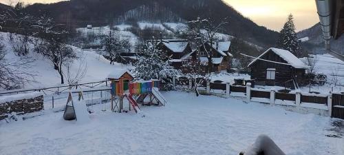 a snow covered village with houses and a fence at Cabana Valea Sadului in Rau Sadului