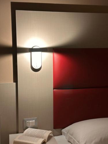 a bedroom with a bed with a red headboard and a light at Hotel City 20 in Milan