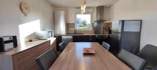 a kitchen with a wooden table and a refrigerator at Maison plain-pied Calme et Nature in Cuvier