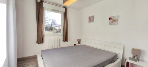 a white bedroom with a bed and a window at Maison plain-pied Calme et Nature in Cuvier