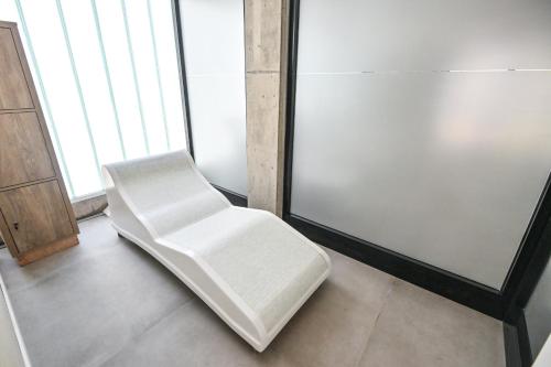 a white chair sitting in a room with windows at Hotel Denver Mar del Plata in Mar del Plata