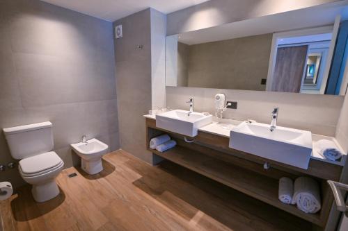 a bathroom with two sinks and a toilet and a mirror at Hotel Denver Mar del Plata in Mar del Plata