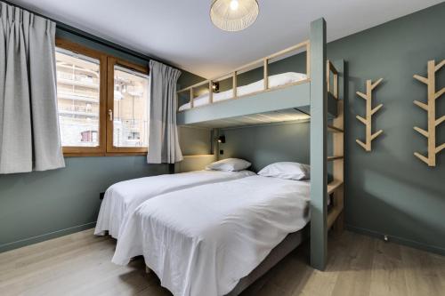 une chambre avec un lit superposé avec des draps blancs dans l'établissement Résidence Maison Neuve - Appartement rénové·Pied des pistes·Balcon·Parking MAE-0391, à Tignes