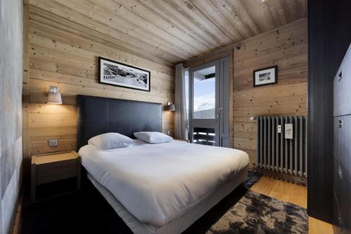 une chambre avec un grand lit dans une pièce aux murs en bois dans l'établissement Résidence Hauts Du Val Claret B2 - Appartement renové·Pied des pistes·Balcon MAE-3641, à Tignes