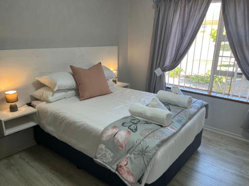 a bedroom with a bed and a large window at Rose Manor, Hartenbos Heuwels in Mossel Bay