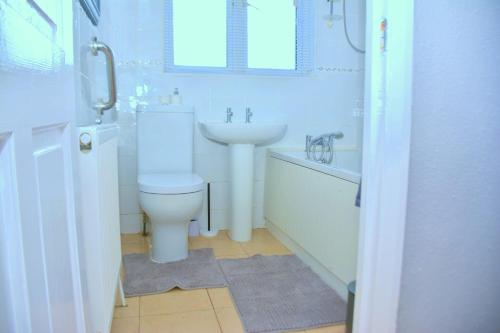 a white bathroom with a sink and a toilet at Time Space Bliss in Dagenham Dock
