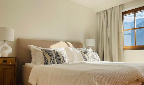 a white bedroom with a bed with pillows and a window at Ferienwohnungen Lukaserhof in Mieming