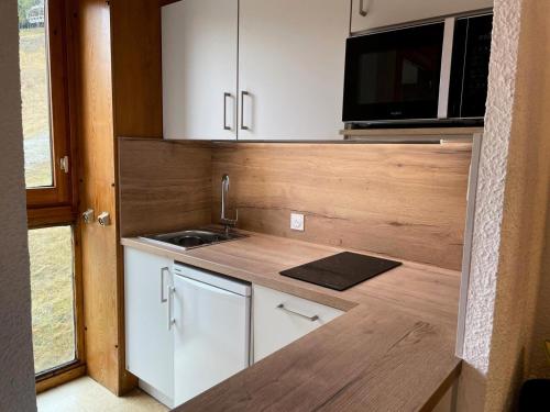 une petite cuisine avec un évier et un micro-ondes dans l'établissement Résidence La Clef - Appartement au coeur des Coches MAE-0181, à Aime La Plagne