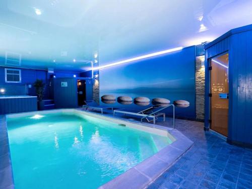 - une piscine dans une maison à l'éclairage bleu dans l'établissement Gîte bien-être avec piscine, spa et sauna à Gussignies - FR-1-510-223, à Gussignies