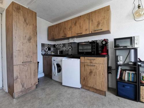 une cuisine avec des armoires en bois et une laveuse et une sécheuse dans l'établissement Résidence Le Carlton - 2 Pièces 4 couchages PORT LEUCATE. Réf: 2CAR_128AC MAE-0911, à Leucate