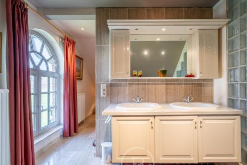 a bathroom with two sinks and a window at Countryhouse Blauw in De Panne