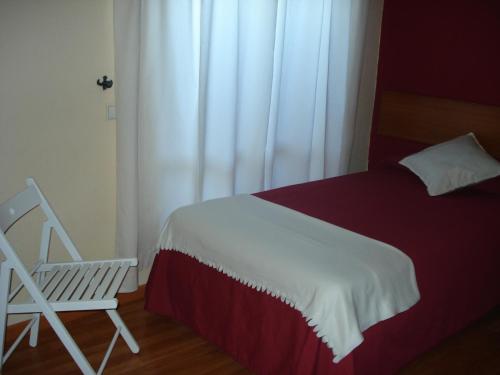 a bedroom with a bed and a white chair at Guesthouse RSA by Umbral in Almancil