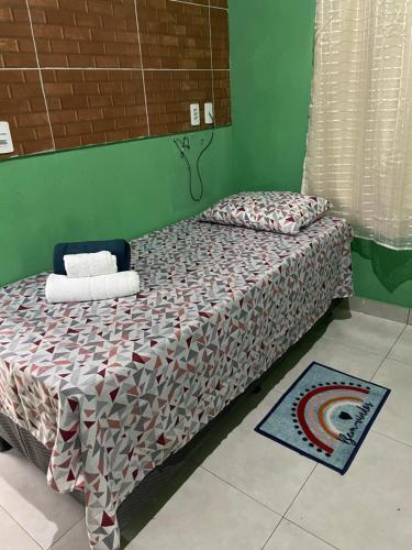 a bed with a comforter on it in a room at Casa fechada in Pirenópolis