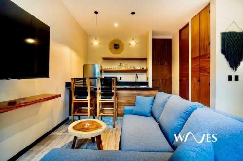 a living room with a blue couch and a kitchen at Natural Lighted Boho Chic Studio with Private Pool by Waves in Tulum