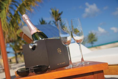 Una botella de champán y dos copas en una mesa. en Jalsa Beach Hotel & Spa, en Poste Lafayette