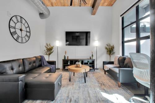 a living room with couches and a clock on the wall at Industrial Loft Living 2BR 2BA in Greenville