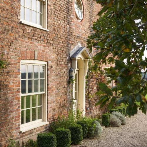 a brick building with two windows and some bushes at Brills Farm in Lincoln