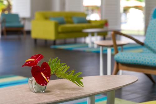 a vase with a red flower sitting on a table at Kauai Shores Hotel in Kapaa