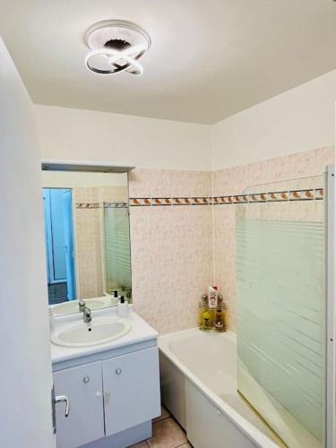 une salle de bain avec un lavabo et une baignoire et un lavabo dans l'établissement Chic Appartement Design et Securise avec parking, Proche Paris I CDG, au Bourget