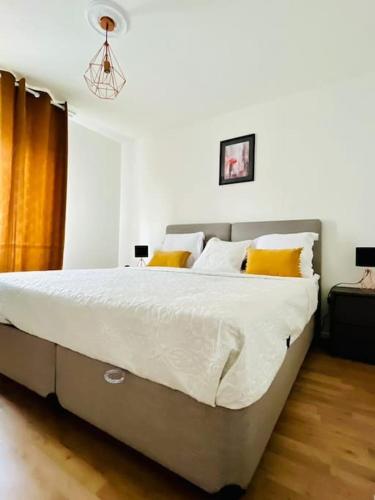 une chambre avec un grand lit avec des oreillers jaunes dans l'établissement Chic Appartement Design et Securise avec parking, Proche Paris I CDG, au Bourget