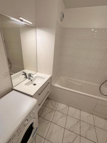 La salle de bains blanche est pourvue d'un lavabo et d'une baignoire. dans l'établissement La Colombe, à Colombes