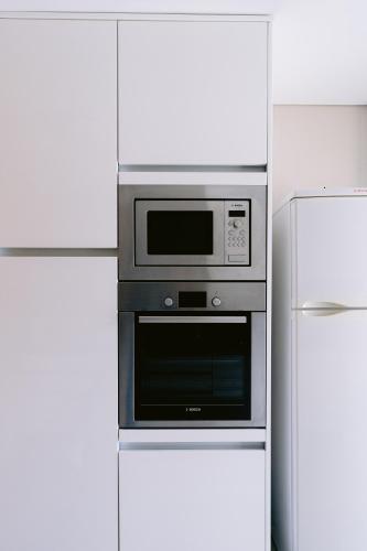a microwave in a kitchen next to a refrigerator at White Family House in Aveiro
