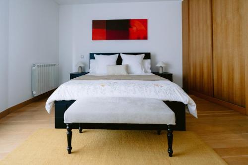 a bedroom with a bed with a white comforter at White Family House in Aveiro