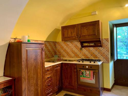 a kitchen with wooden cabinets and a stove top oven at La Casa Nel Borgo in Pettorano sul Gizio