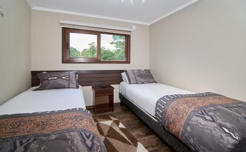 two beds in a room with a window at Mirabosque aparment Ejecutivos 8 in Osorno
