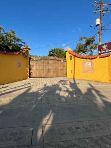 a yellow building with a gate and a fence at El Ensueño Ecohostal & Glamping in Mocoa