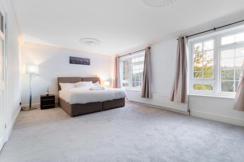 a white bedroom with a bed and two windows at Purley House-Sleeps 8-Near Gatwick-Games Room in Purley