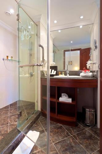 a bathroom with a glass shower and a sink at Jalsa Beach Hotel & Spa in Poste Lafayette