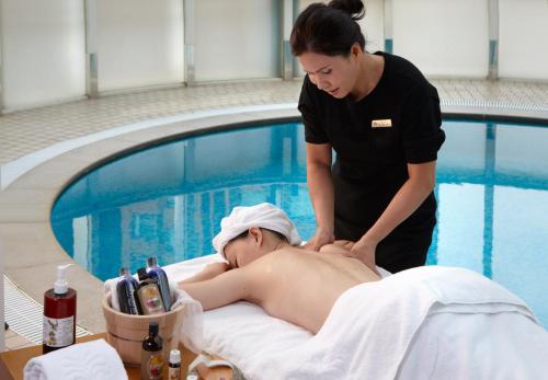 a woman giving a man a massage by a swimming pool at Hotel Royal Hsinchu in Hsinchu City