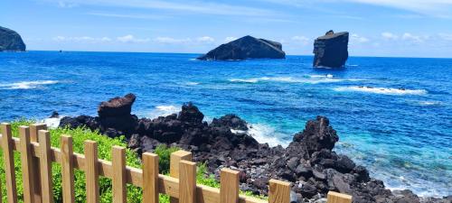 a wooden fence overlooking the ocean with black rocks at Azure Loft 2 in Mosteiros