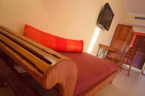 a bedroom with a wooden bed with a red pillow at Jalsa Beach Hotel & Spa in Poste Lafayette
