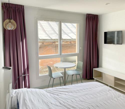 - une chambre avec un lit, une table et deux chaises dans l'établissement Studio proche gare et sanctuaire, à Lourdes