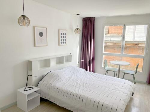 une chambre avec un lit, une table et une fenêtre dans l'établissement Studio proche gare et sanctuaire, à Lourdes