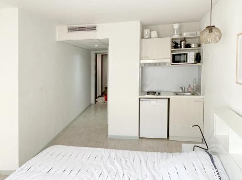 - une cuisine blanche avec un lit dans une chambre dans l'établissement Studio proche gare et sanctuaire, à Lourdes