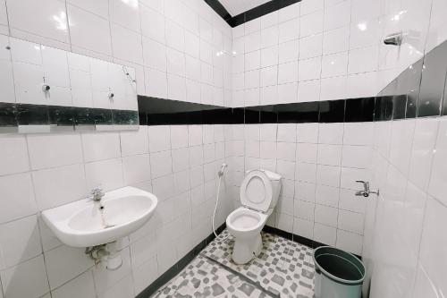 a white bathroom with a sink and a toilet at Scala Inn By Helocus in Medan