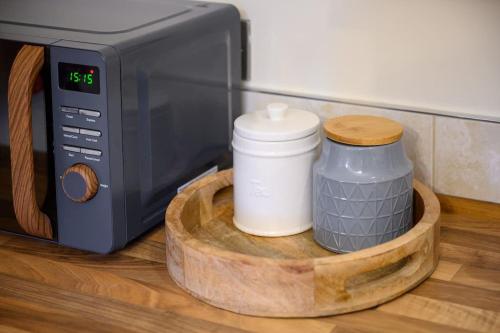 a toaster oven with two jars in front of a microwave at Charming Luxury Apartment Peak District in Matlock