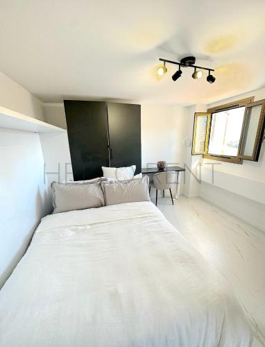 a large white bed in a room with a table at Studio confort Business 20m2 - 2 min a pied de Monaco in Beausoleil