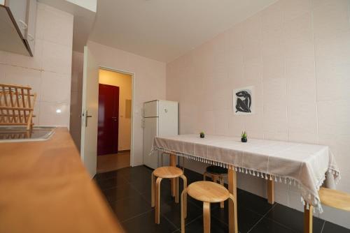 Il comprend une cuisine équipée d'une table avec tabourets et d'un réfrigérateur. dans l'établissement Appartement confortable et lumineux à Belleville, à Paris