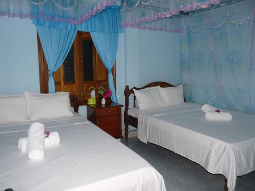 two beds in a room with blue walls and blue curtains at Cham Island Smiles Homestay in Tân Hiệp
