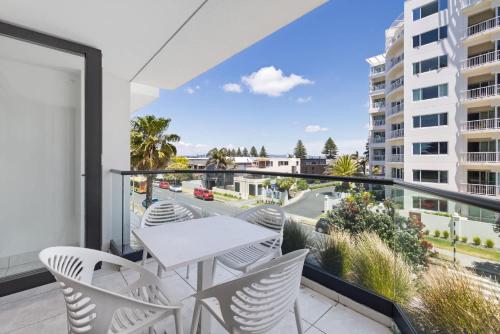 a balcony with a table and chairs and a view of a city at Ocean Eleven Mt Maunganui in Mount Maunganui