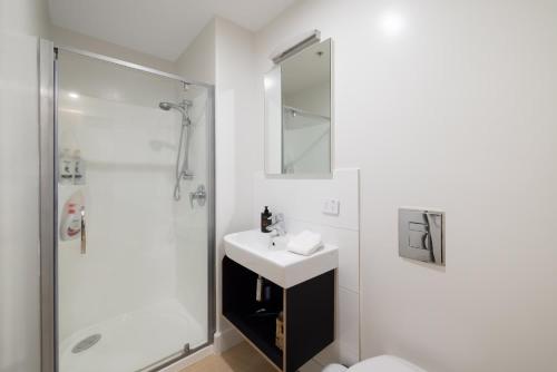 a white bathroom with a sink and a shower at Ocean Eleven Mt Maunganui in Mount Maunganui