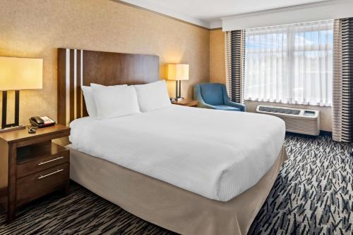 a hotel room with a large bed and a chair at Best Western Plus Pitt Meadows Inn & Suites in Pitt Meadows